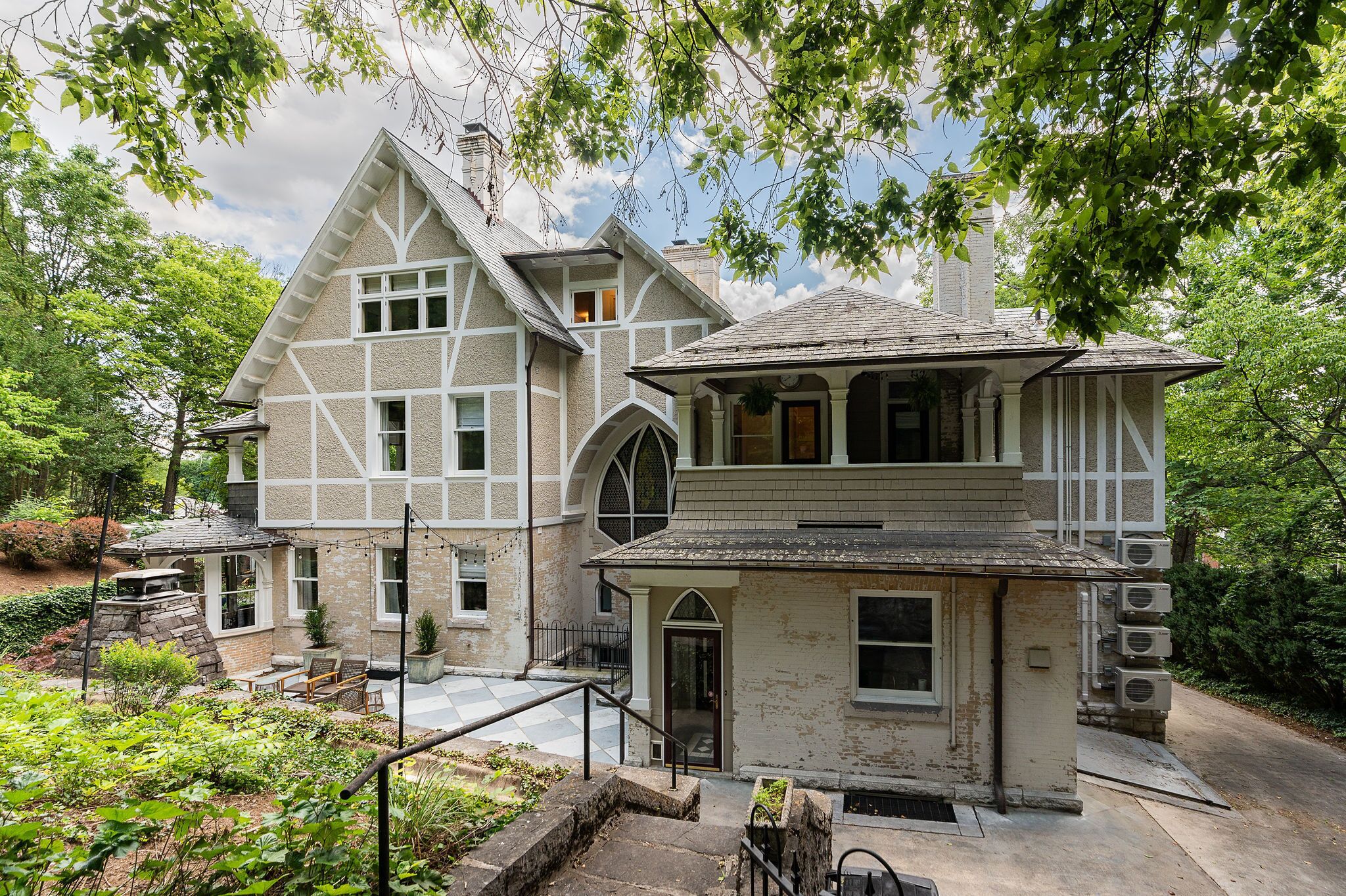 A large, two-story house with a steep gabled roof, multiple windows, and a small porch.