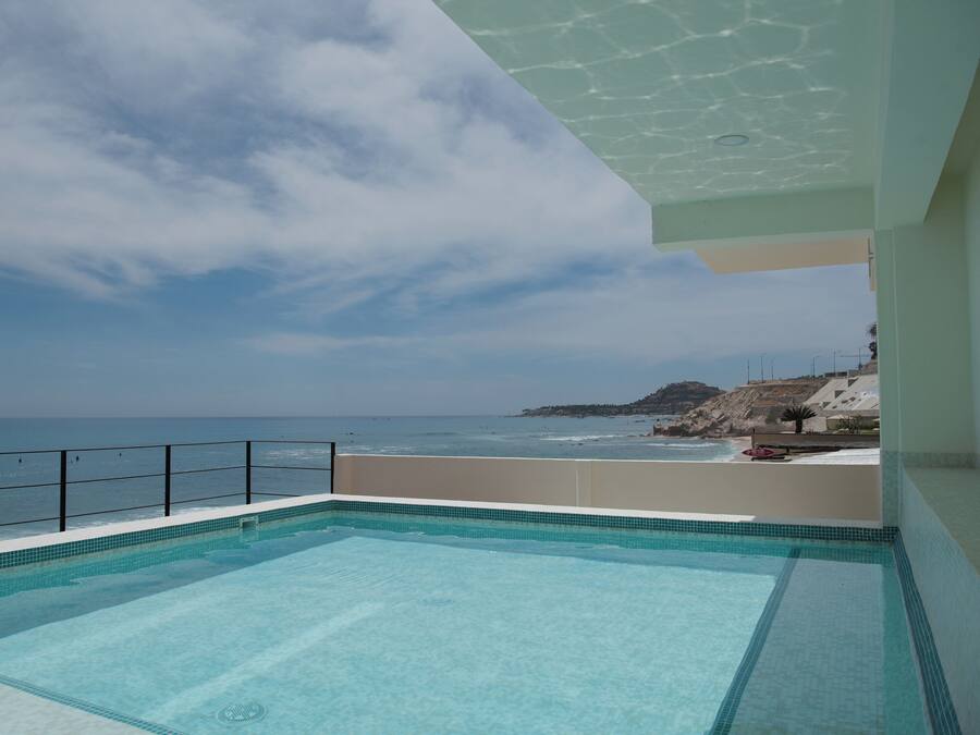 A swimming pool with a view of the ocean and a rocky landscape in the background.