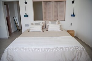 Un dormitorio con una cama grande, un armario y un espejo.