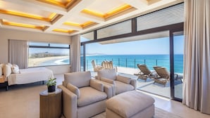 A modern hotel room with a large balcony overlooking the sea, a bed, a sofa, and a small side table with a plant. - Cabo Break Hotel (San José del Cabo)