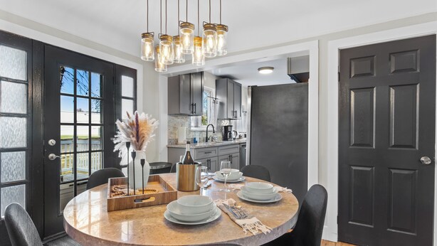 A dining area with a round table, black chairs, and a chandelier. - The Drift House- Spacious Boho Family Retreat- 4 bds, 2 baths, 6 TVs, Movie Room (Clinton Township)