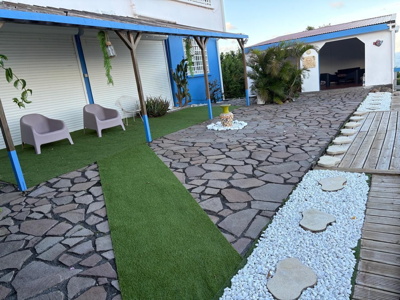 A patio with artificial grass, stone paving, and a wooden deck.