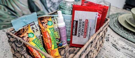 A wicker basket containing various food items and a bottle of Kirkland Micro Wave popcorn butter.