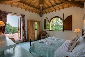 Ein Schlafzimmer mit Bett, Stuhl, Schreibtisch und Blick ins Freie.