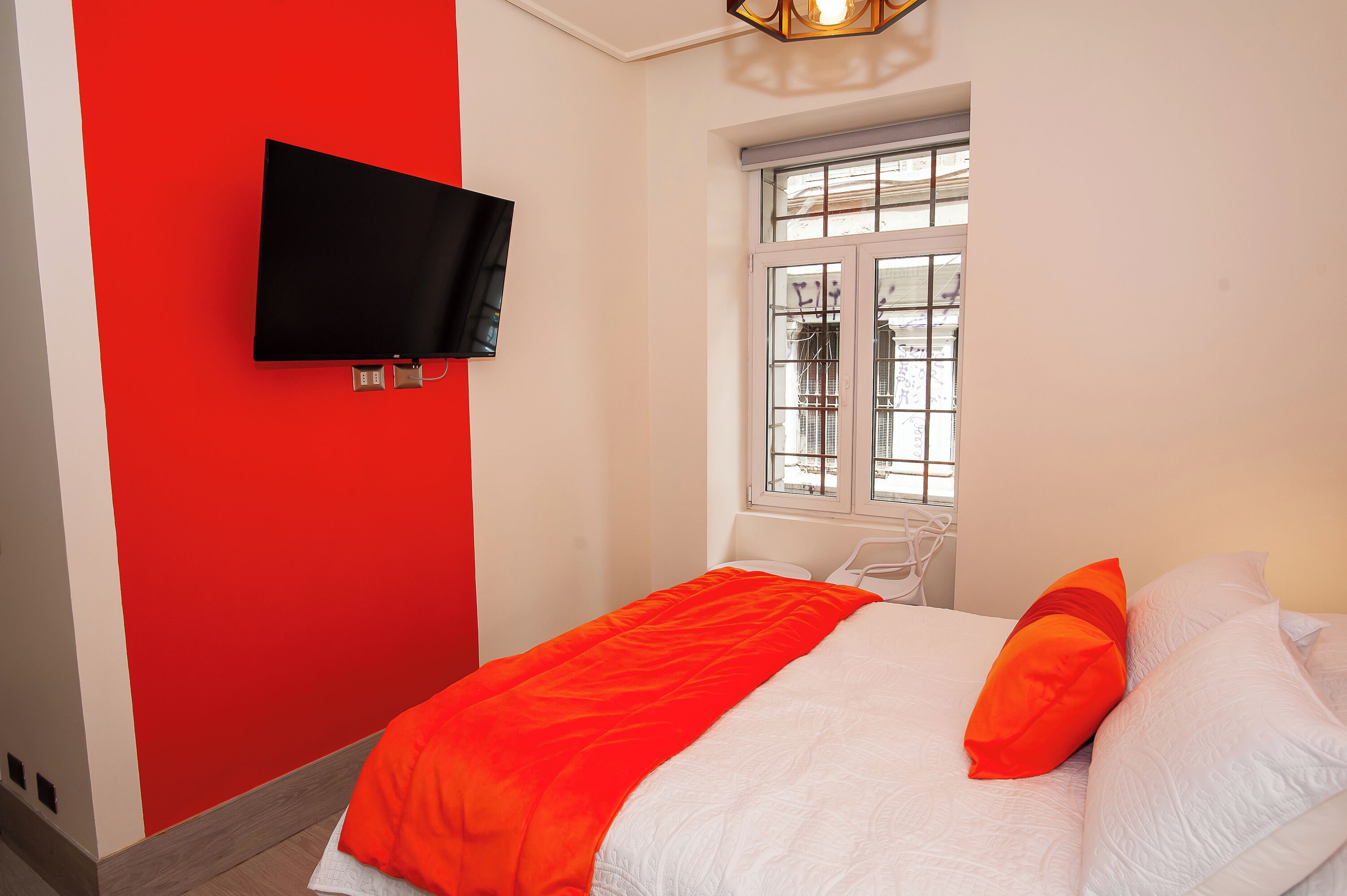 Ein Zimmer mit einem Bett, einem an der Wand montierten Fernseher und einem Fenster mit Blick.