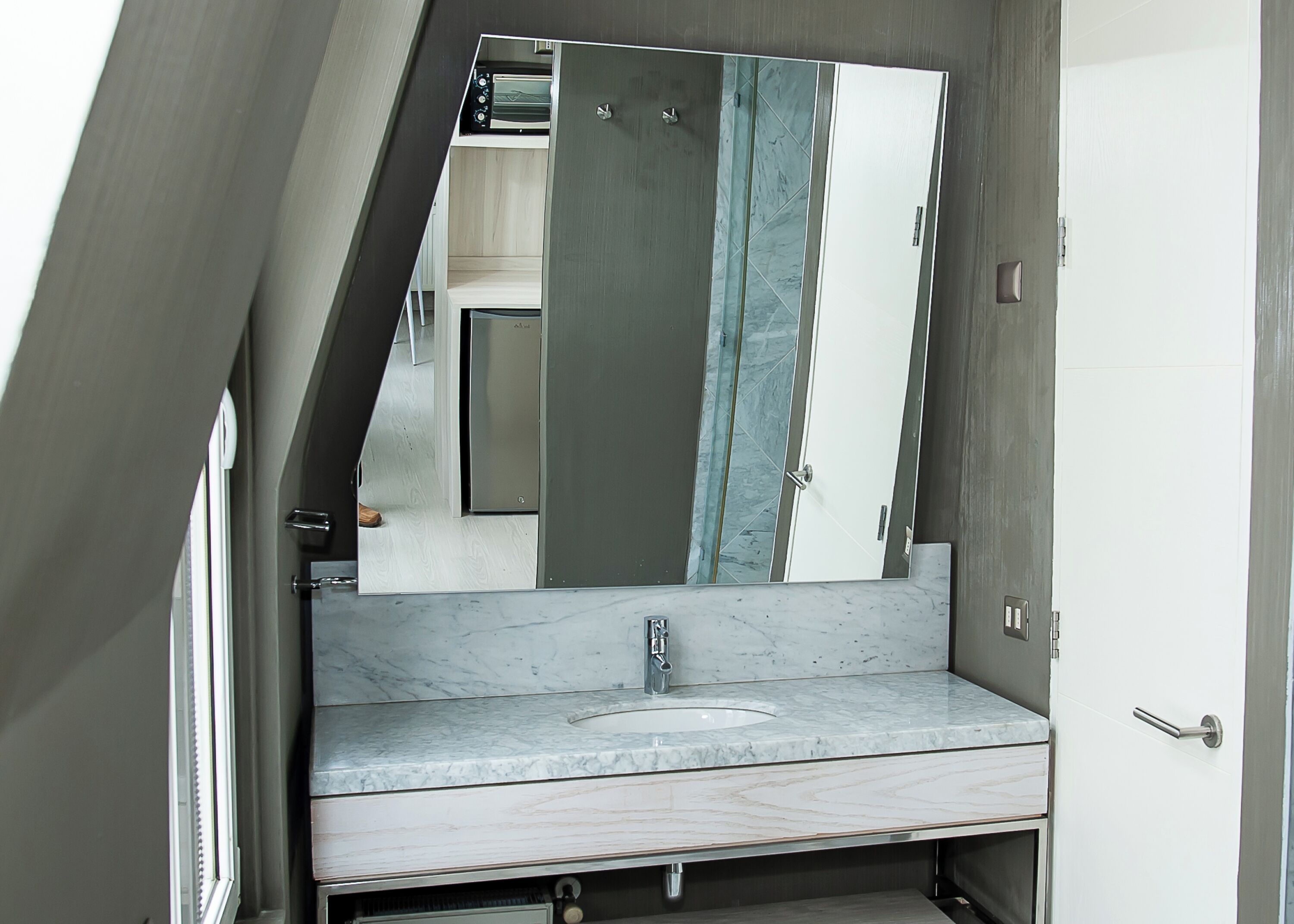 A bathroom with a marble sink, a large mirror, and a door with a handle.