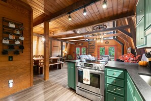 A spacious kitchen with a central island, wooden beams, and a view of the outdoors.