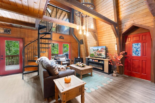 A cozy cabin interior with a fireplace, a sofa, a coffee table, and a TV.