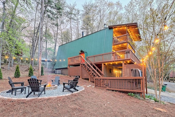 A cabin with a wooden deck, outdoor seating, and a fire pit.