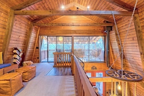 A wooden interior with a balcony, a staircase, and a hanging light fixture.
