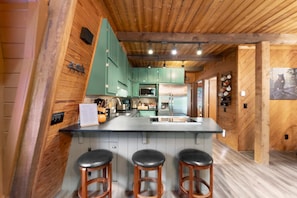 A kitchen with wooden walls, a central island with stools, and modern appliances.
