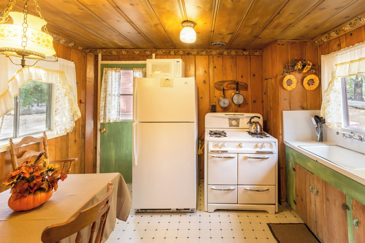 Une cuisine avec des murs en bois, un réfrigérateur, une cuisinière et un évier.