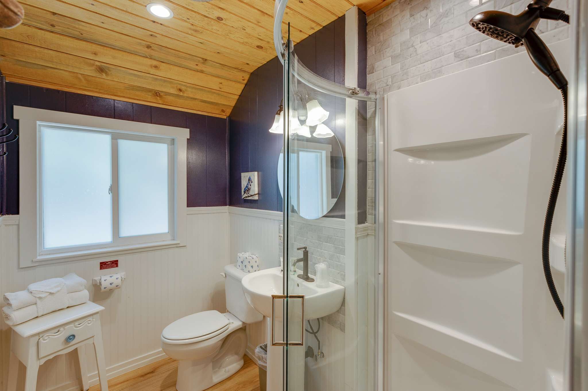 A bathroom with a glass shower enclosure, a white sink, and a toilet.