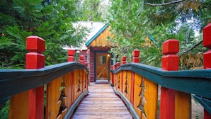 Un puente de madera con barandillas rojas que conduce a una cabaña.