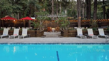 A pool area with lounge chairs and a pergola with string lights.