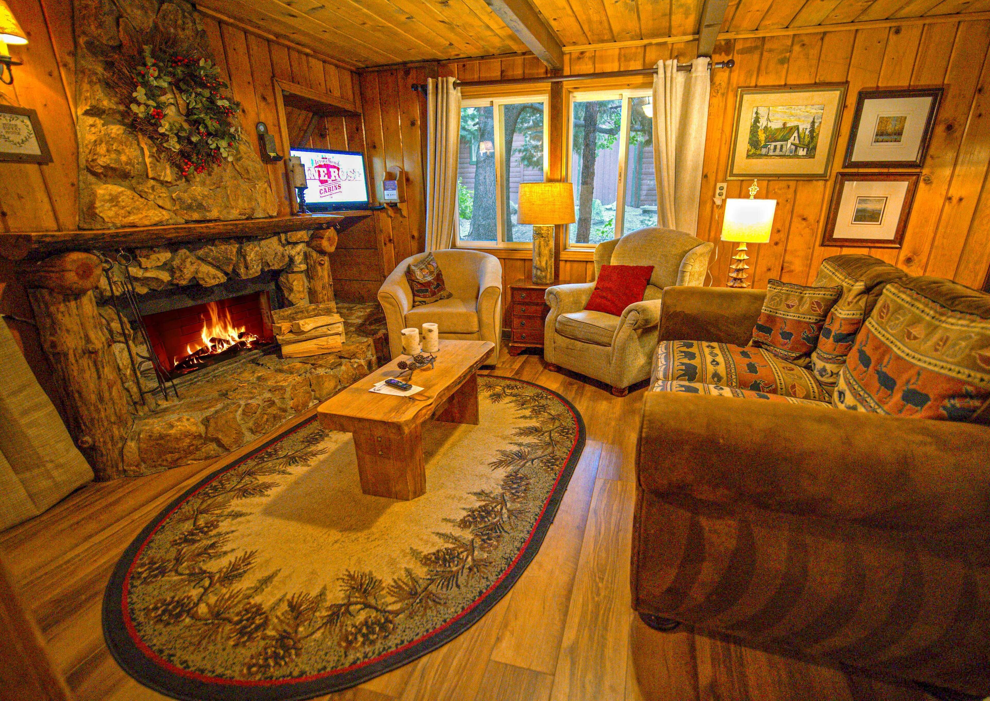 Een gezellig cabin interieur met een stenen open haard, houten wanden, een televisie en een comfortabele zithoek.