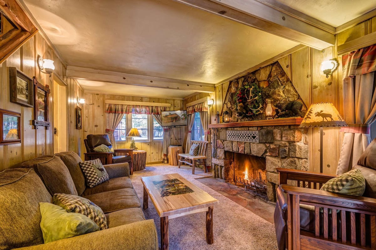 Un salon chaleureux avec une cheminée, des murs en bois et un coin salon confortable.