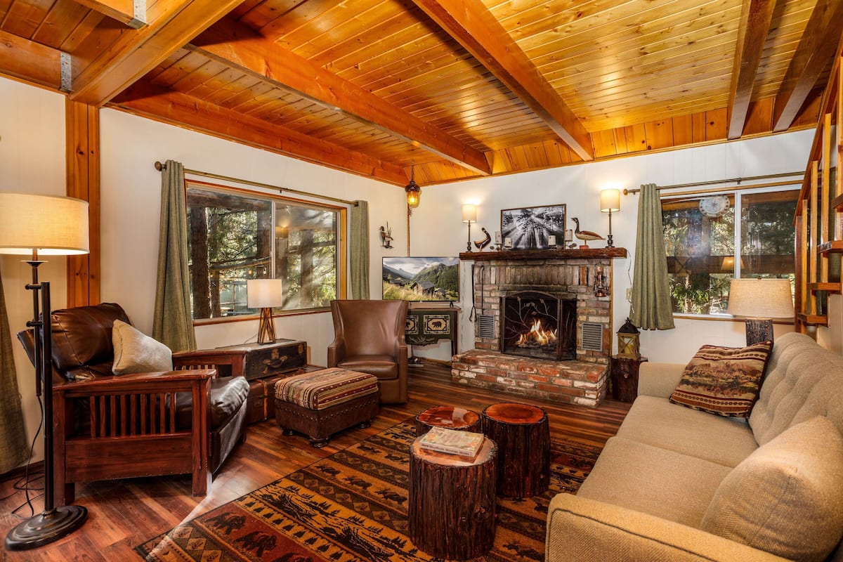 Un salon chaleureux avec une cheminée, des meubles en bois et une vue sur l’extérieur.