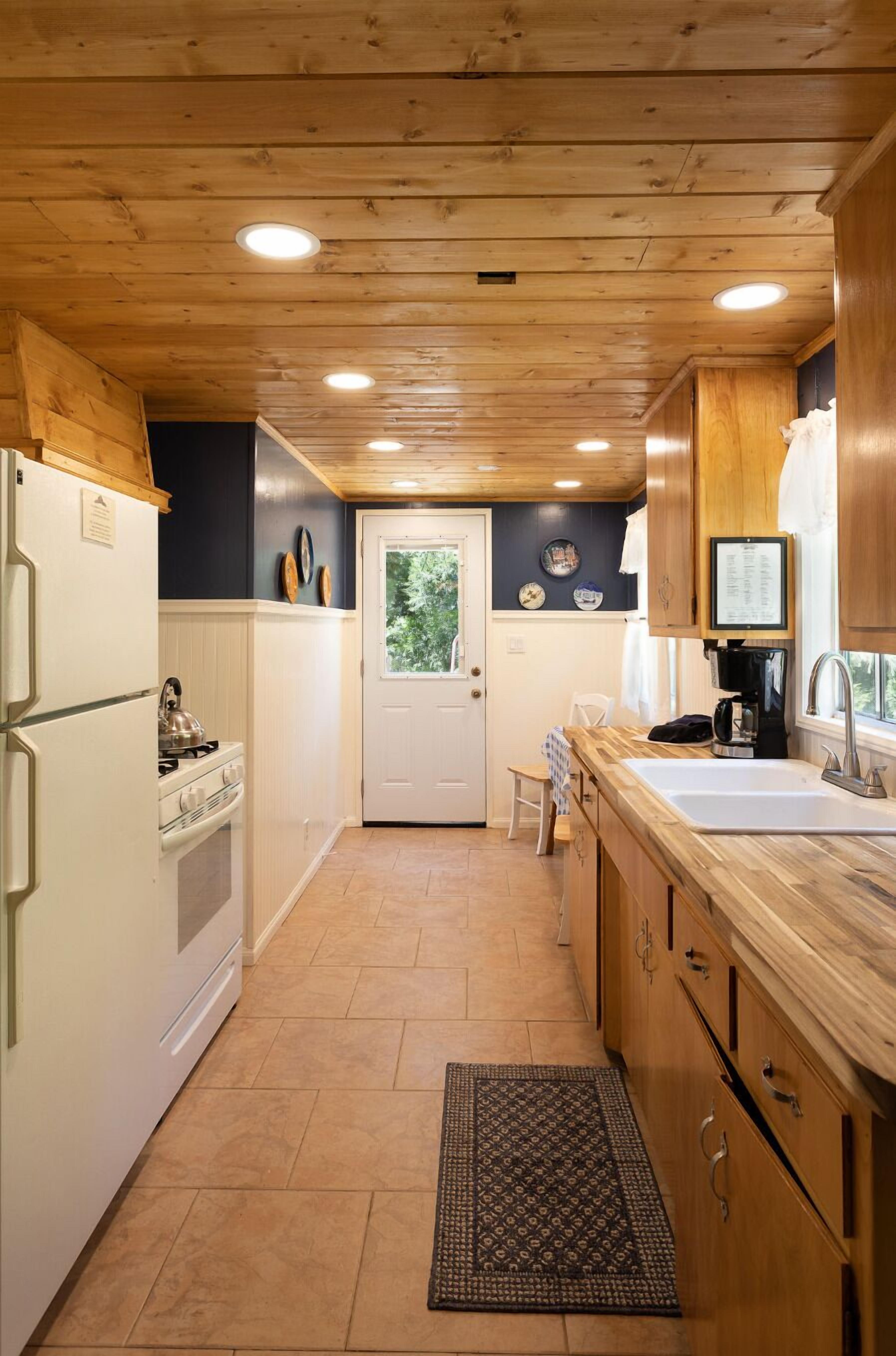 A compact kitchen with wooden cabinets, a white refrigerator, a stove, and a sink.