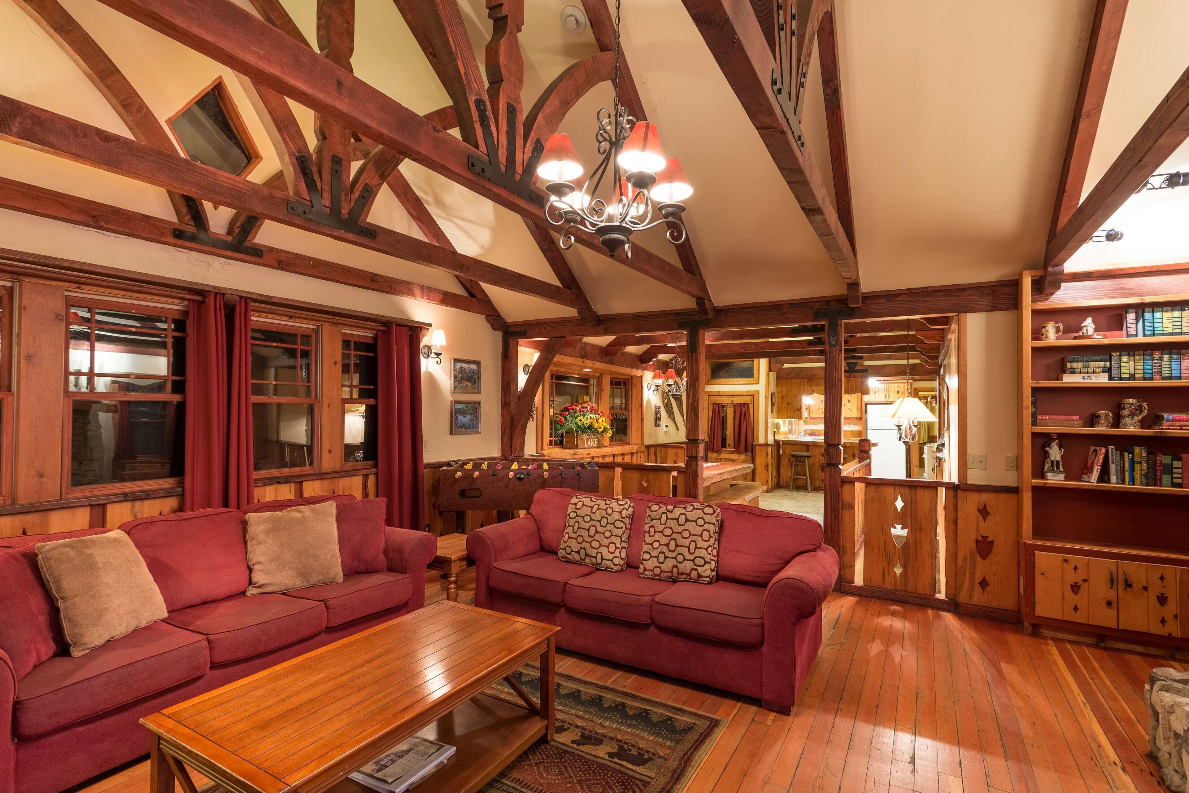 Una habitación acogedora con vigas de madera, un sofá rojo, una mesa de centro de madera y una estantería.
