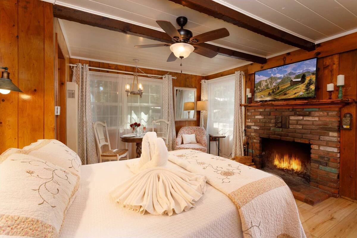 Une chambre confortable avec un grand lit, une cheminée et un ventilateur de plafond.