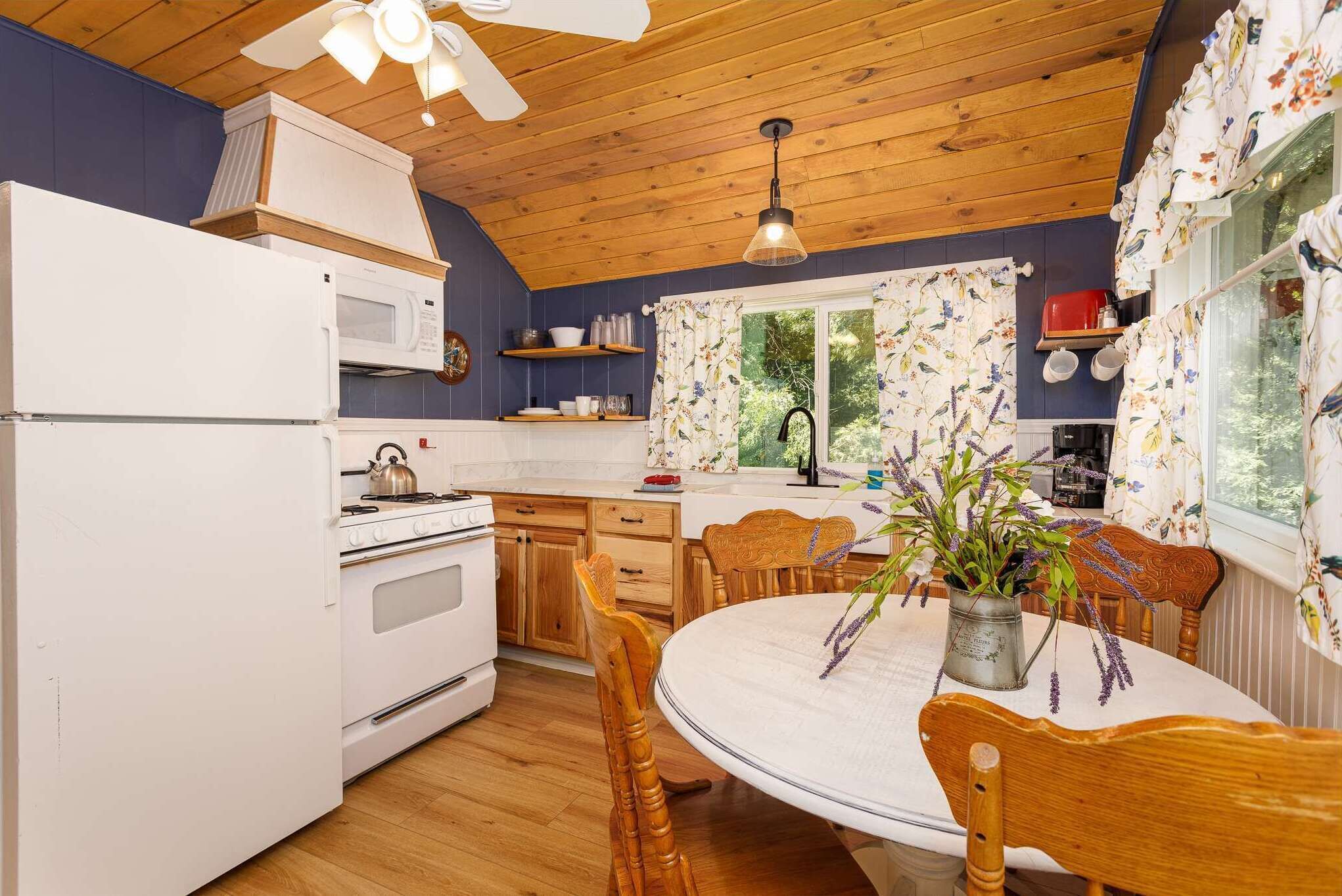 A kitchen with wooden cabinets, a white refrigerator, a stove, and a dining table with chairs.
