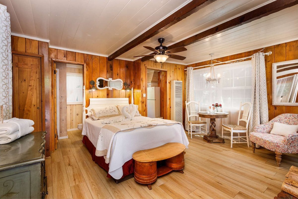 Une pièce chaleureuse en bois, avec un lit, une petite table et deux chaises.