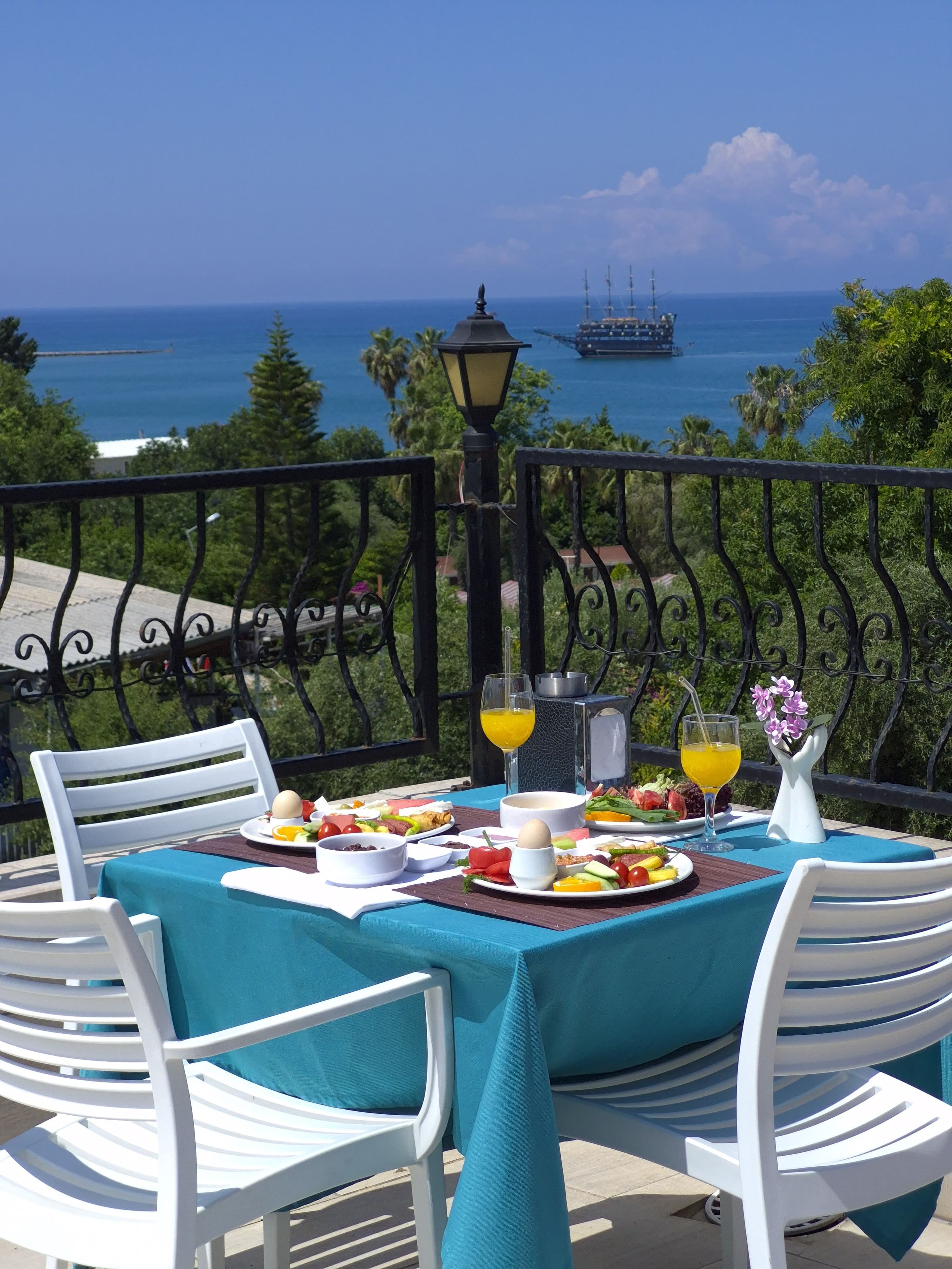 A table set with breakfast items, overlooking a coastal view with a ship in the distance.