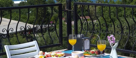A table set with breakfast items, overlooking a coastal view with a ship in the distance.