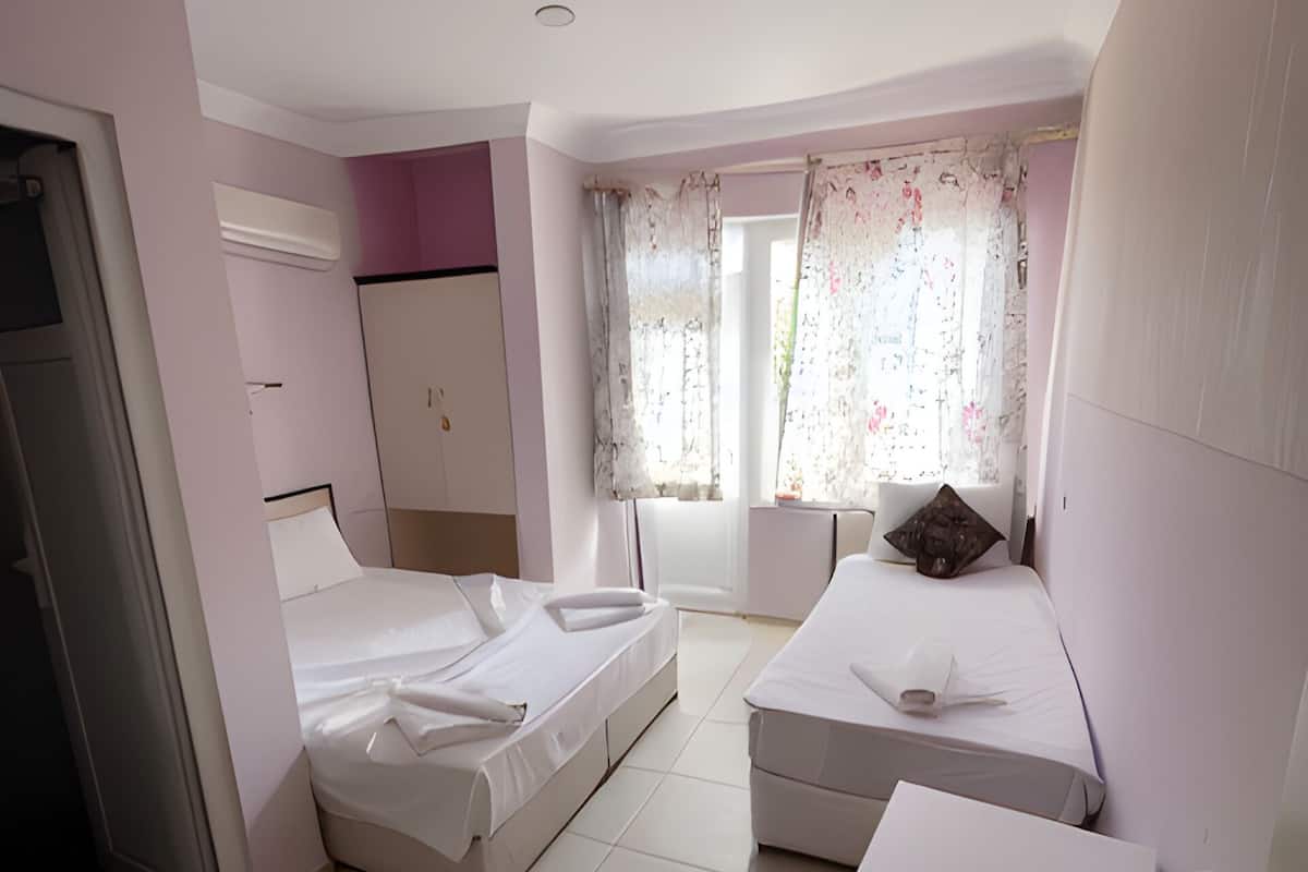 A bedroom with two single beds, a small desk, and a wardrobe.