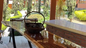 Un plafond en bois, agrémenté d’un luminaire suspendu, et une vue sur un jardin avec un banc et un panier en osier.