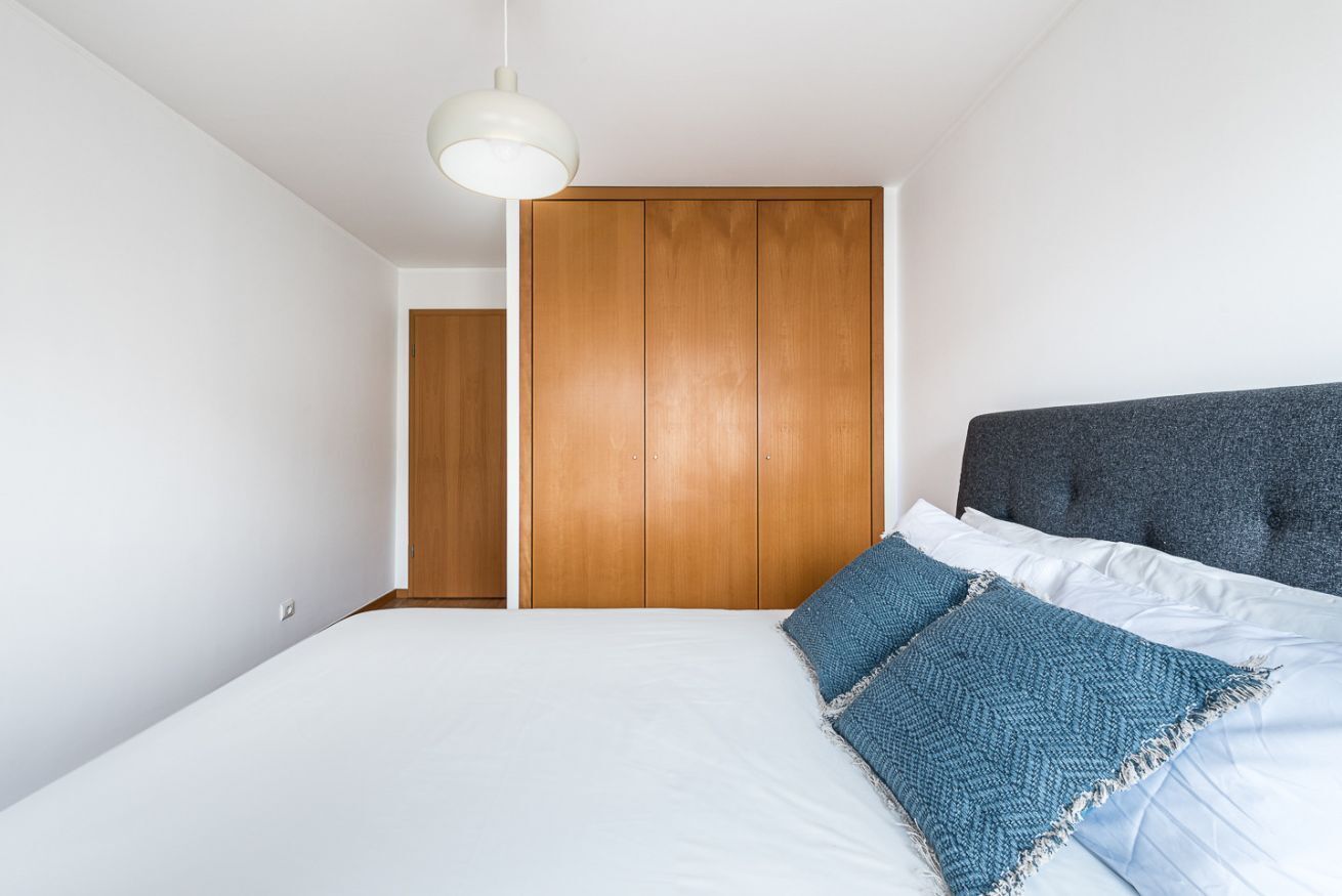 Ein Schlafzimmer mit einem Bett, einem Holzschrank und einem grauen Kopfteil.
