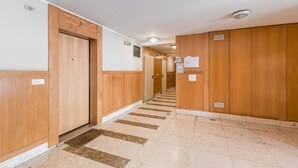 Een hotelgangen met houten lambrisering, een betegelde vloer en een deur met daarop 