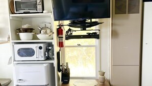 Un espai vital compacte amb una cuineta, un televisió de pantalla plana, un refrigerador petit i una finestra amb vistes.