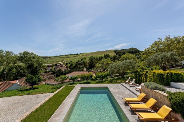 An outdoor swimming pool with a clear view of the surrounding landscape, including houses and greenery.