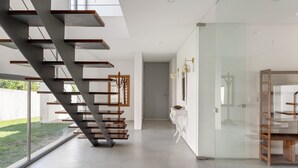 A modern interior with a staircase, a glass partition, and a minimalist design.