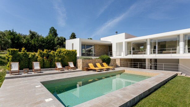A modern house with a swimming pool, outdoor seating, and a well-maintained garden.