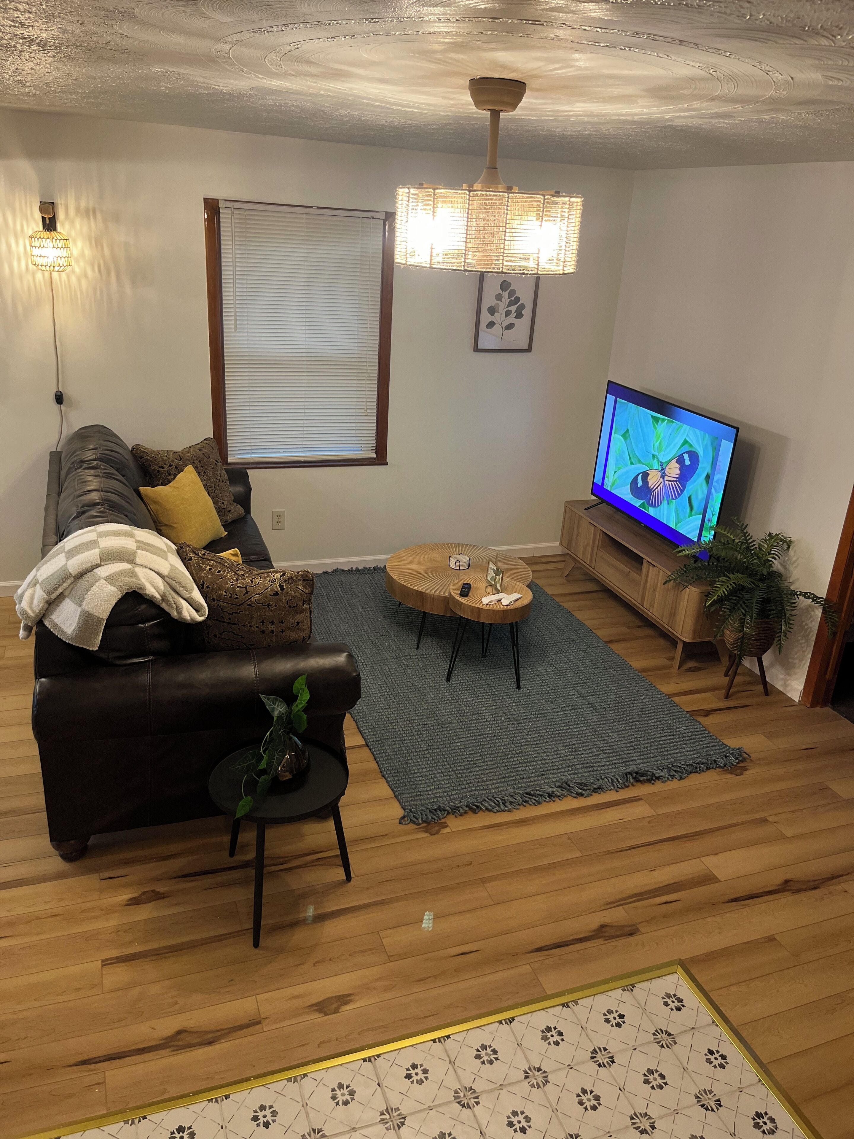 A living room with a leather sofa, a coffee table, a TV, and a patterned rug.