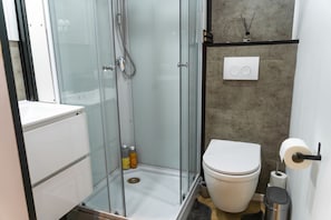 Ein modernes Badezimmer mit einer Duschkabine, einer Toilette und einem Waschbecken.