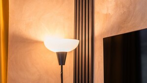 A wall-mounted lamp with a white shade against a textured wall.