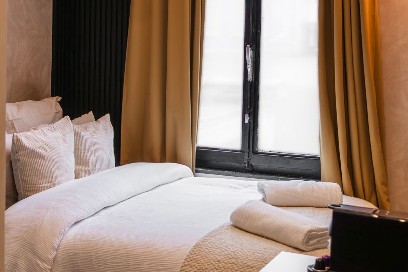 Una habitación de hotel con una cama grande, un escritorio con ordenador y una ventana con cortinas.