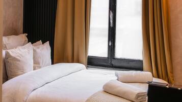 Una habitación de hotel con una cama grande, un escritorio con ordenador y una ventana con cortinas.