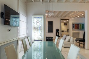 Une salle de conférence moderne avec une table en verre, des chaises blanches, un grand téléviseur et une fenêtre décorative en verre.