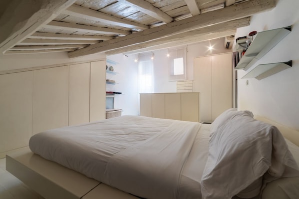 Un dormitorio con cama, armario empotrado y una ventana pequeña.