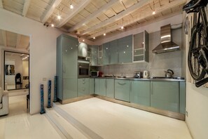 Una cocina moderna con armarios verde claro, electrodomésticos de acero inoxidable y una estufa a la vista.