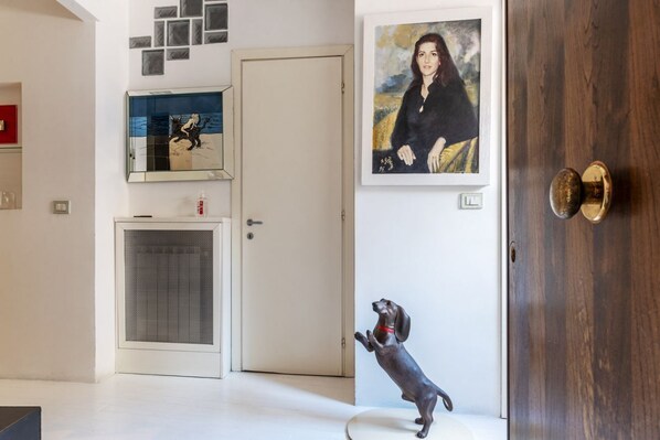 A modern interior with a dog statue, a door, and a framed portrait on the wall.
