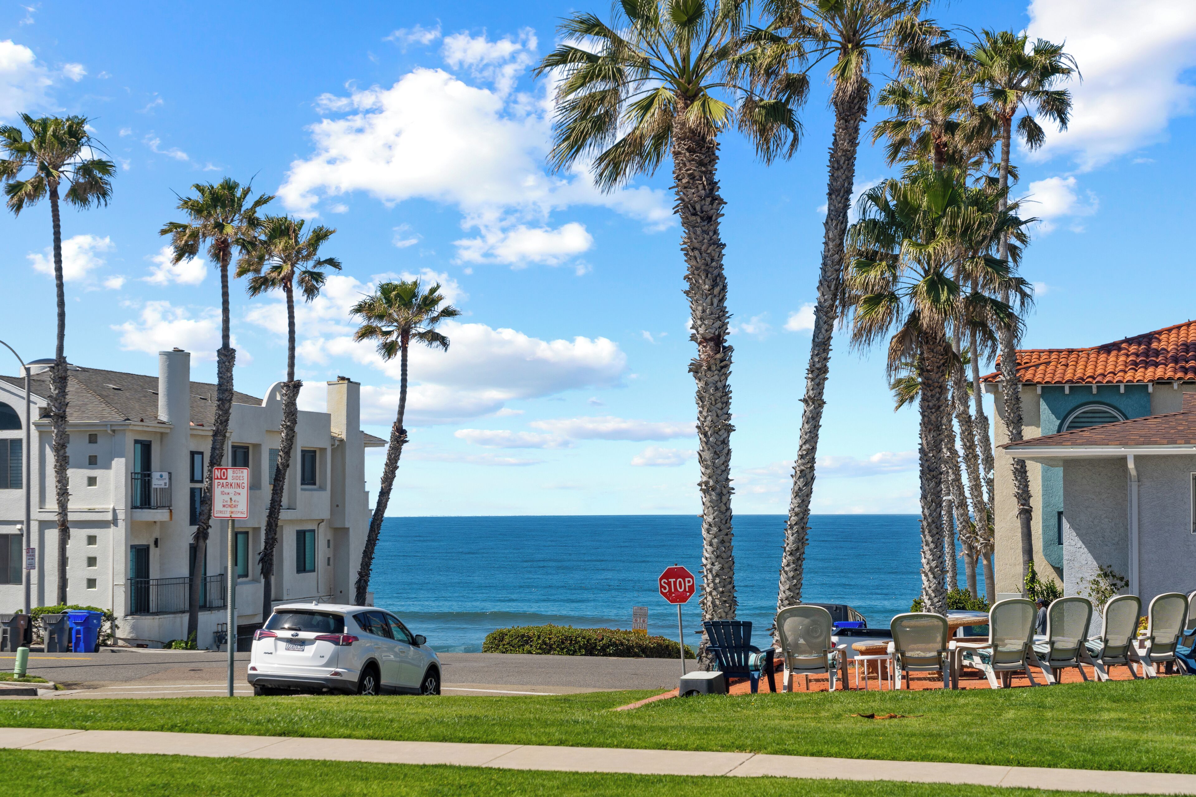 A coastal hotel with a view of the ocean, palm trees, and a stop sign.