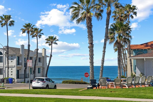 A coastal hotel with a view of the ocean, palm trees, and a stop sign. - California Dreamin' - O'side Palms (Oceanside)
