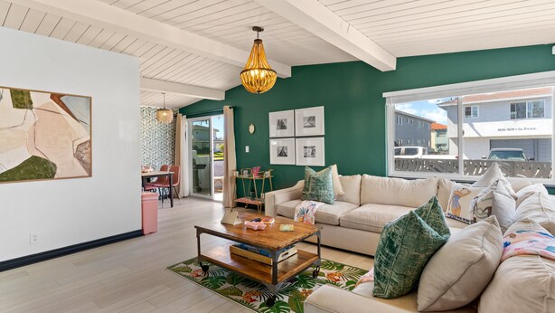 A spacious living room with a green accent wall, a white ceiling, and a large window. - Amazing Place by the Sea - O'side Palms (Oceanside)