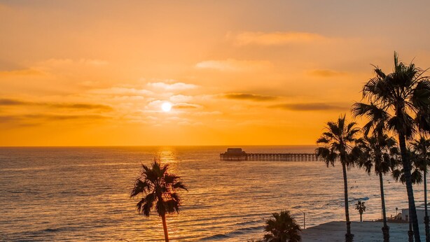 A sunset view over the ocean with palm trees and a pier. - Beach Meets Fabulous - O'side Palms (Oceanside)